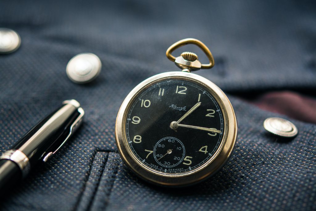 round silver-colored and black pocket watch displaying 1:15