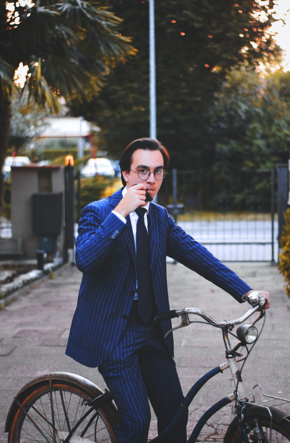 man in a suit riding bicycle during daytime while smoking a pipe